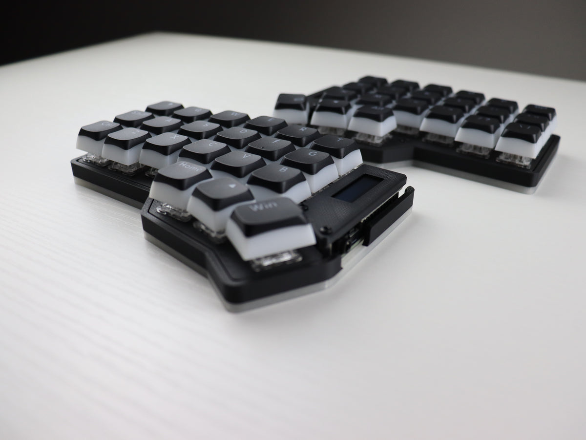 Mechanical keyboard with black and white keycaps on a light surface