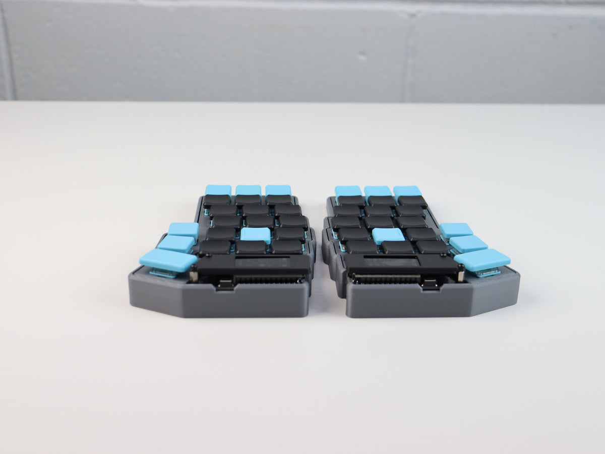 Two modular device components with blue and black keycaps on a white background