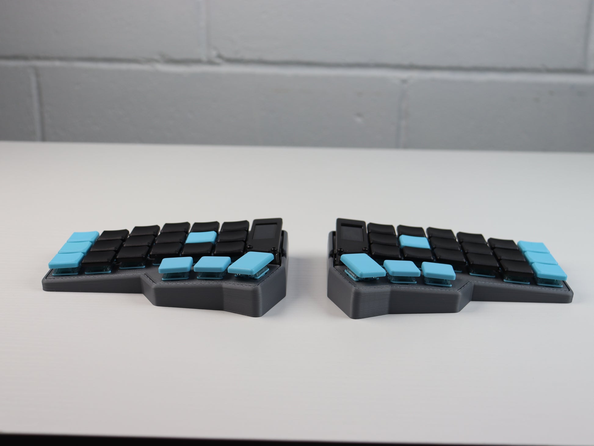 Corne Choc wireless split ergonomic keyboard — two-piece low-profile design with black and cyan keycaps, columnar stagger layout, thumb cluster keys, and small OLED display on each half