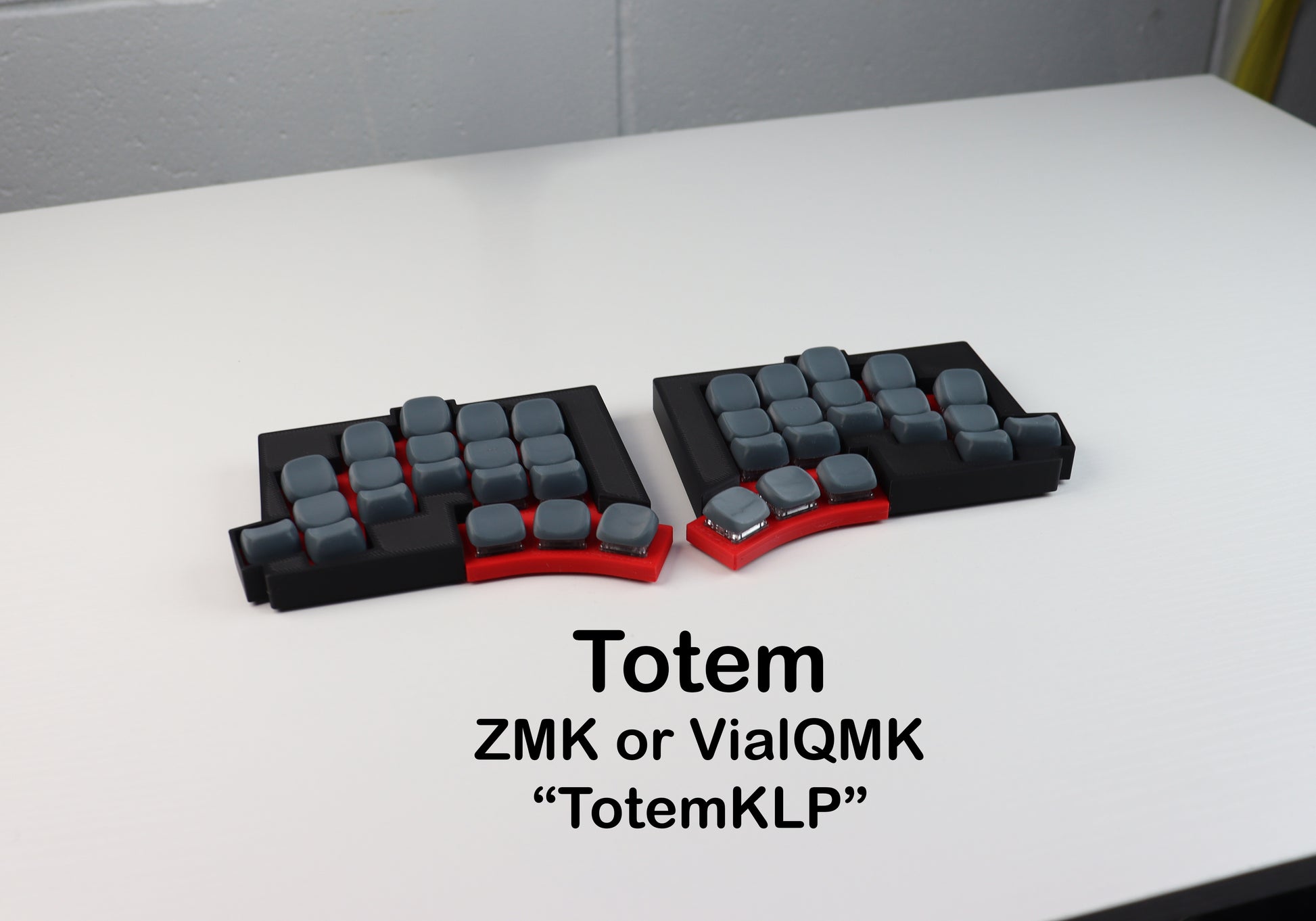 Two black and gray keycaps on a white surface with text indicating brand names.